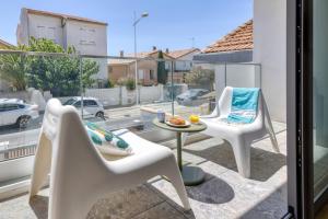 卡诺海滩SOUTH-OF-FRANCE T2 neuf haut de gamme, climatisé, parking gratuit, 2eme ligne balcon的阳台配有2把白色椅子和桌子 更多21张照片