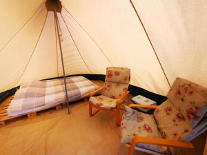 a bedroom with a tent with a bed and two chairs at Volledig ingerichte tent op natuurcamping in Gräsmark