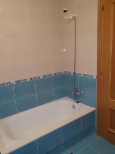 uma banheira na casa de banho com azulejos azuis em Los Coucheiros em Negreira