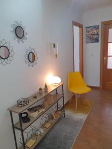 ein Wohnzimmer mit einem Tisch und einem gelben Stuhl in der Unterkunft Los Coucheiros in Negreira