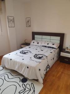 Schlafzimmer mit einem Bett mit einer schwarzen und weißen Bettdecke in der Unterkunft Los Coucheiros in Negreira