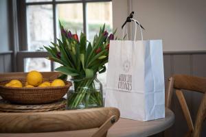 un tavolo con un vaso di fiori e una borsa da shopping di Farriers Cottage-Tranquil Haven, Central Location! a Hexham