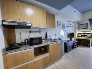 a kitchen with wooden cabinets and a sink and a microwave at Condo Azur Suites A326 Amani Resorts Residences , 5 minutes Airport, Netflix, Stylish, Cozy with Luxurious Swimming Pool in Pusok