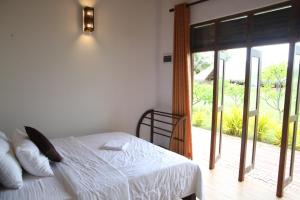 - une chambre avec un lit et une porte coulissante en verre dans l'établissement NN Beach Resort & SPA, à Nilaveli