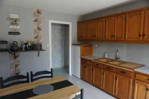 a kitchen with wooden cabinets and a table and a sink at Appartement Davézieux in Davézieux