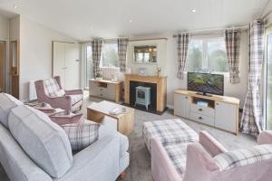 a living room with two couches and a tv at Par Sands Coastal Holiday park in Par