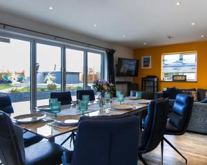 een eetkamer met een lange tafel en stoelen bij Covehithe House-Coastal luxury- sleeps 12-with huge swimspa! in Wrentham