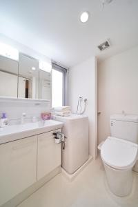 La salle de bains blanche est pourvue de toilettes et d'un lavabo. dans l'établissement Yuzuki Dome Osaka Kujo, à Osaka