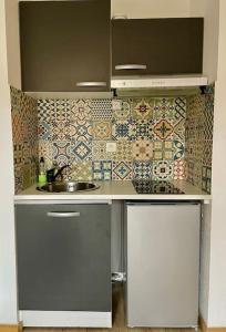 a kitchen with a sink and a tile wall at Studio Sainte Victoire avec balcon in Aix-en-Provence