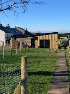 ein Gebäude auf einem Feld mit einem Zaun in der Unterkunft The CowShed Cottage - Beautiful Location in Lancaster
