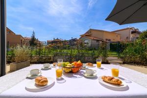 a table with food and a bowl of fruit and orange juice at Villa Ida in Rovinj