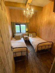 duas camas num quarto com um lustre em The CowShed Cottage - Beautiful Location em Lancaster