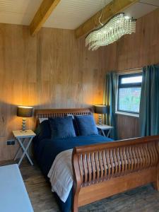 1 dormitorio con 1 cama, 2 mesas y lámpara de araña en The CowShed Cottage - Beautiful Location en Lancaster