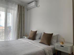 a white bedroom with a bed and a window at Veselinka Apartments & Rooms in Budva