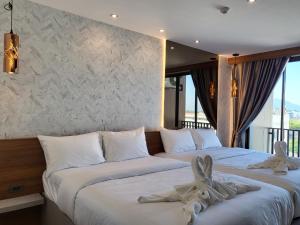 S3 Huahin Hotel في هوا هين: سريرين في غرفة الفندق عليها مناشف