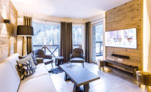 a living room with a couch and a tv at AvenidA Mountain Lodges Saalbach in Saalbach Hinterglemm