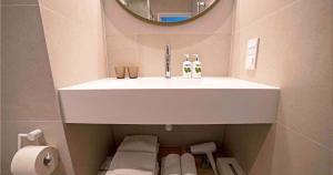 La salle de bains est pourvue d'un lavabo blanc et d'un miroir. dans l'établissement LaSpa Beach House, à Laulasmaa