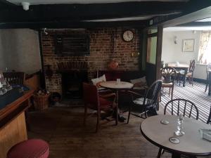 a restaurant with tables and chairs and a fireplace at Glamping At The Fox Inn Bramdean in Bramdean