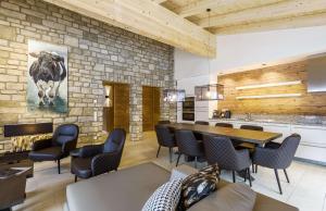 a living room with a table and chairs and a stone wall at AvenidA Mountain Lodges Saalbach in Saalbach Hinterglemm