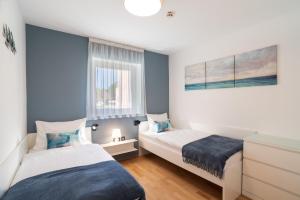 2 camas en una habitación pequeña con paredes azules en Marina Portoroz - Ammonite Apartment by Locap Group, en Portorož
