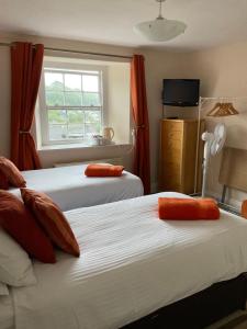 a bedroom with two beds with orange curtains and a window at No 52 bed and breakfast in Helston