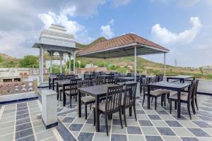 eine Terrasse mit Tischen, Stühlen und einem Pavillon in der Unterkunft OYO Flagship 77120 Hotel Achrol Haveli Sukher in Udaipur