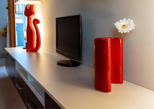 deux vases rouges assis sur un bureau avec une télévision dans l'établissement Appartamento incantevole con parcheggio privato, à Casteldidone
