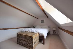 a attic bedroom with a bed and a wicker trunk at Down End Cottage, Corfe Castle in Corfe Castle