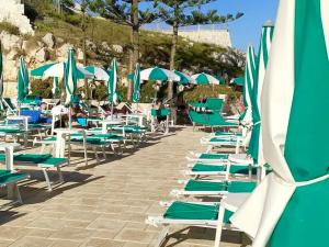 uma fila de cadeiras e guarda-sóis numa praia em Casa Porta D'oriente em Santa Cesarea Terme