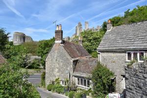an old stone house with a castle in the background at Down End Cottage, Corfe Castle in Corfe Castle +13 photos