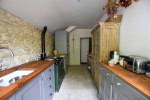 a kitchen with a counter and a sink and a stone wall at Down End Cottage, Corfe Castle in Corfe Castle