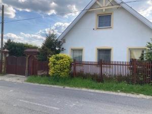 a white house with a wooden fence next to it at Sonnen FEWO in Pannonhalma