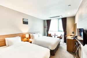 平沢市にあるThe Interra Hotel Pyeongtaekのベッド2台、薄型テレビが備わるホテルルームです。