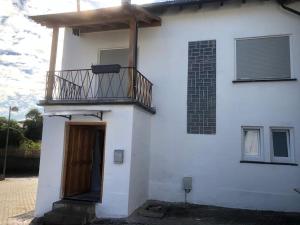 a white house with a balcony on top of it at Sinan's Bio Tourismus Farm Appartement in Betteldorf