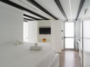 Cette chambre comprend un lit blanc et une télévision murale. dans l'établissement Edison Penthouse By CanariasGetaway, à Las Palmas de Gran Canaria