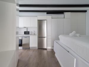 a white kitchen with a bed and a refrigerator at Edison Penthouse By CanariasGetaway in Las Palmas de Gran Canaria