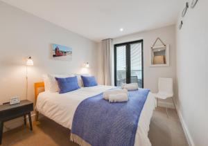 a bedroom with a large bed with blue pillows at 10 Ocean Point in Croyde