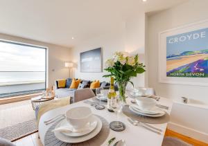 a dining room with a table and a living room at 10 Ocean Point in Croyde