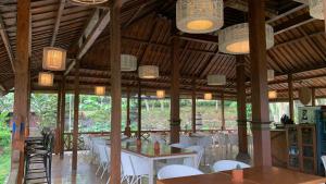 un restaurante con sillas blancas, mesas y luces en Khayangan Resort Yogyakarta, en Balong
