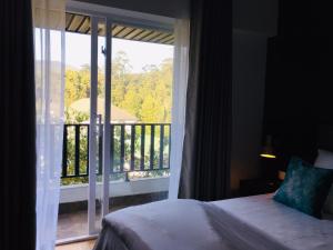 a bedroom with a bed and a view of a balcony at The Greens Luxury Apartment in Nuwara Eliya