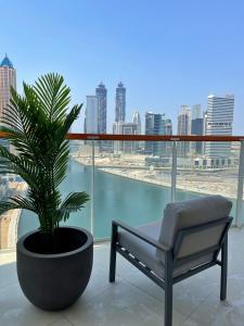 una silla y una planta en un balcón con vistas en Dubai Canal Burj khalifa view 2bedroom apartment, en Al Ḩamīdīyah