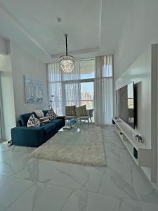 a living room with a blue couch and a large window at Dubai Canal Burj khalifa view 2bedroom apartment in Al Ḩamīdīyah