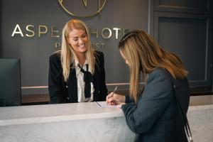 two women standing at a counter writing on a paper at Aspect Hotel Park West in Clondalkin 