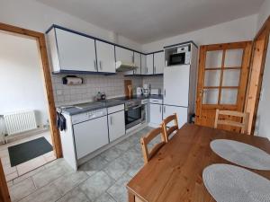 uma cozinha com electrodomésticos brancos e uma mesa de madeira em Ferienwohnung Nordseemond em Norden