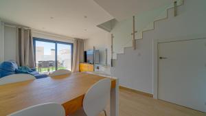 a living room with a table and chairs and a staircase at Duplex Finestrat in Finestrat