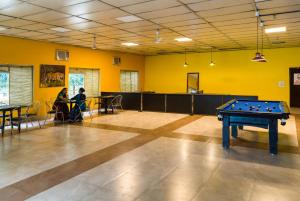 a room with a pool table and people sitting at tables at Manu Maharani Resort in Rāmnagar
