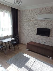 ein Wohnzimmer mit einem Sofa und einem TV an der Wand in der Unterkunft Konyaaltı Tunç Apart in Antalya