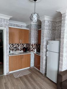 cocina con armarios de madera y nevera blanca en Konyaaltı Tunç Apart, en Antalya