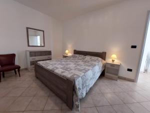 a bedroom with a bed and a chair and a mirror at Appartamento a 150 mt dal lungomare in Leuca