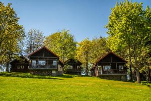 a row of cottages on a green field with trees at Zatoka Kal in Węgorzewo